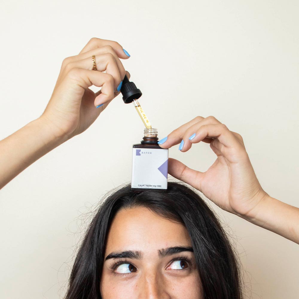 girl taking a dropper of the oil out of the bottle.