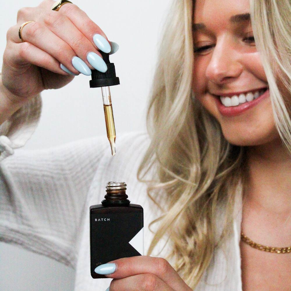 girl holding cbg and cbd oil tincture and smiling 